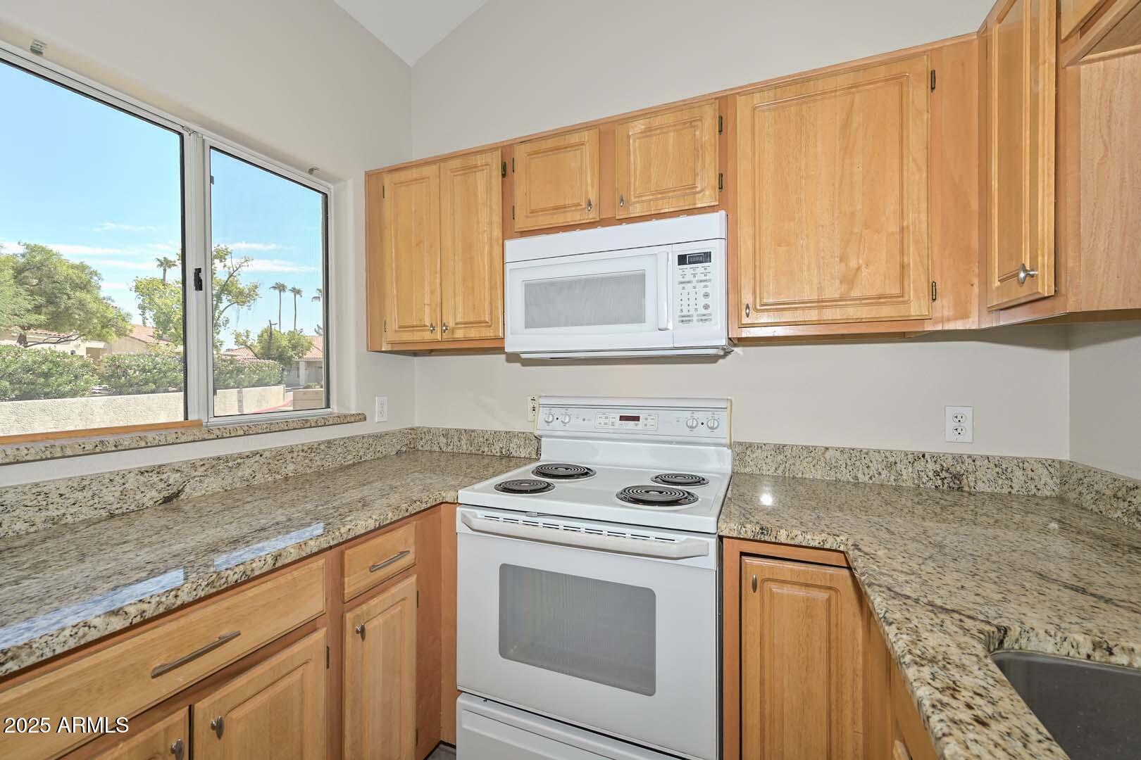 7101 West Beardsley Road, Unit 1104 Glendale, AZ 85308 - Photo 6 of 40 a kitchen with granite countertop cabinets stainless steel appliances a sink and a window