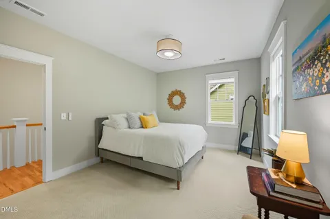 a bedroom with a bed and a lamp on dresser
