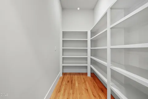 a walk in closet with wooden floor