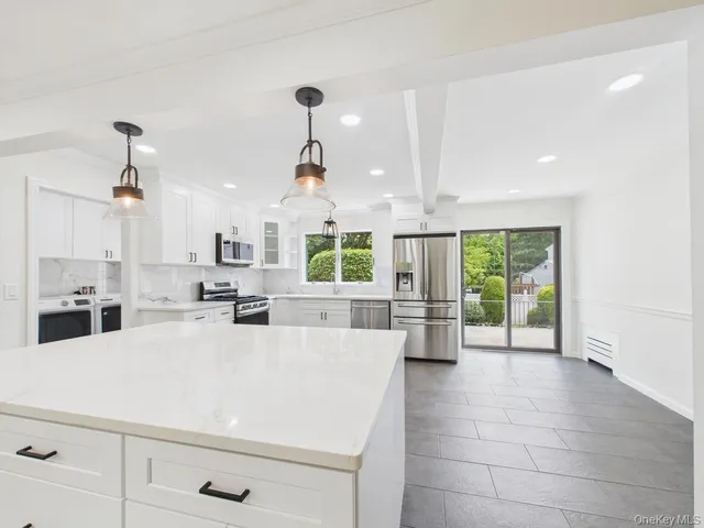 a large white kitchen with a large window appliances and cabinets