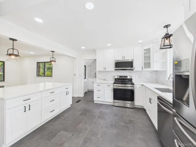 a large kitchen with stainless steel appliances granite countertop a stove and a sink