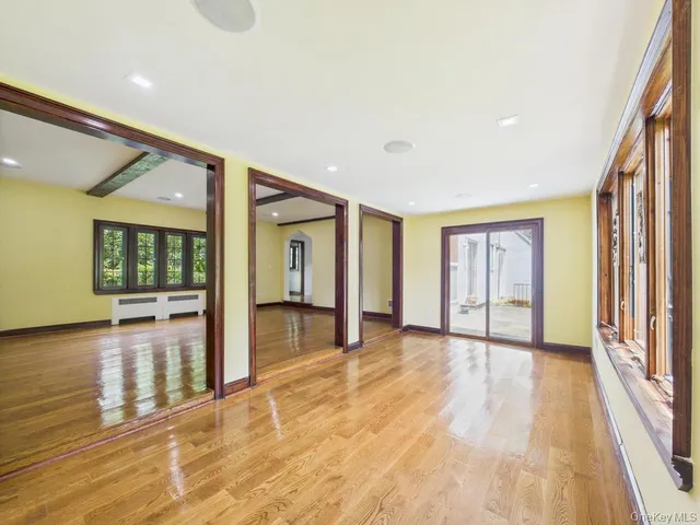 a view of an empty room with window and wooden floor