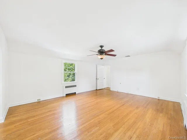 a view of a room with a wooden floor and a ceiling fan