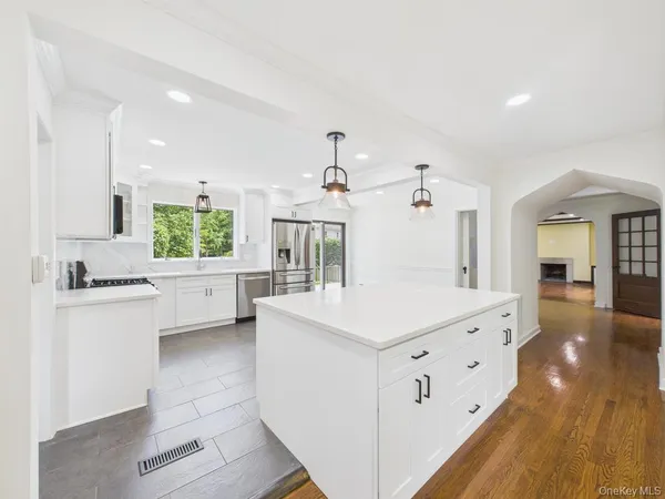 a kitchen with kitchen island a sink a stove a refrigerator and white cabinets
