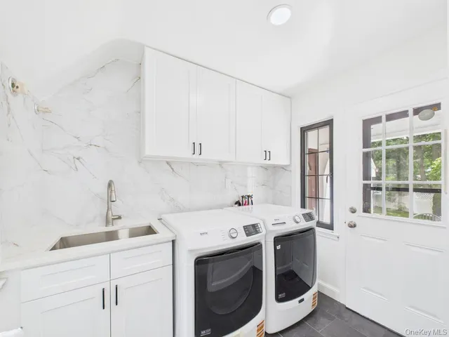 a utility room with stainless steel appliances white cabinets and a sink