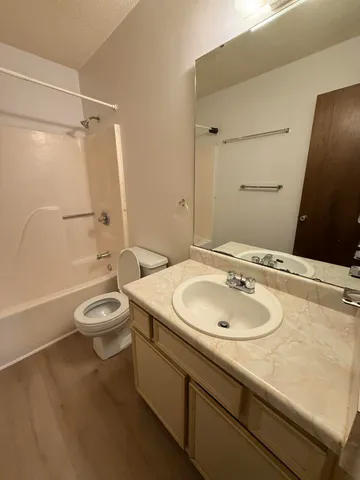 a bathroom with a granite countertop sink a toilet a mirror and shower