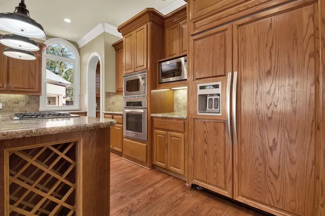 a kitchen with stainless steel appliances granite countertop a refrigerator and wooden cabinets