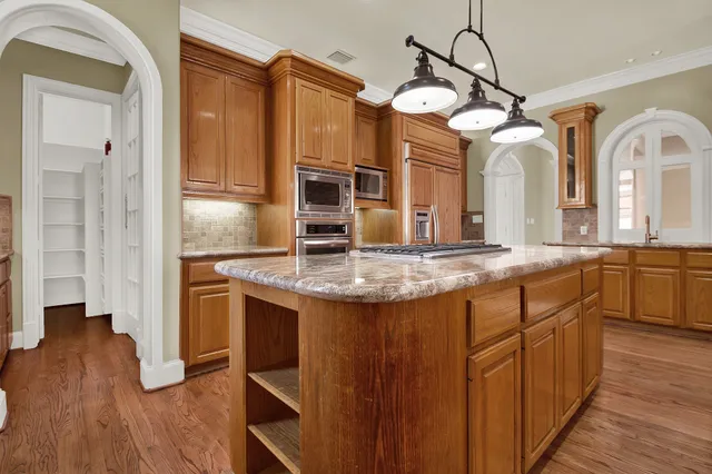 a kitchen with stainless steel appliances granite countertop a sink a oven and a refrigerator with wooden floor
