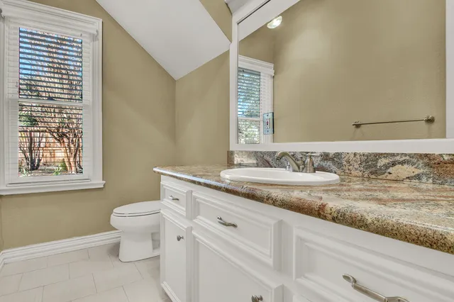 a bathroom with a granite countertop sink mirror vanity and toilet