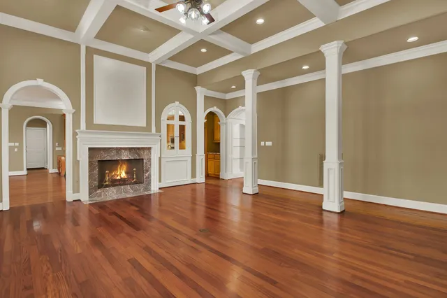 a view of an empty room with wooden floor a fireplace and a window