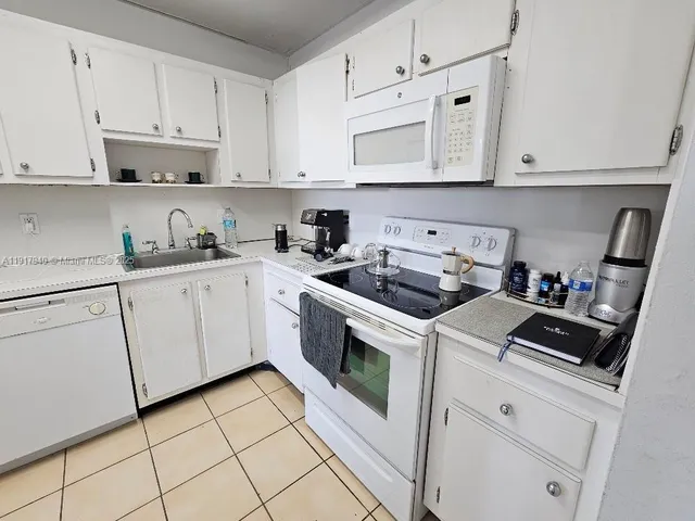a kitchen with white cabinets and white appliances
