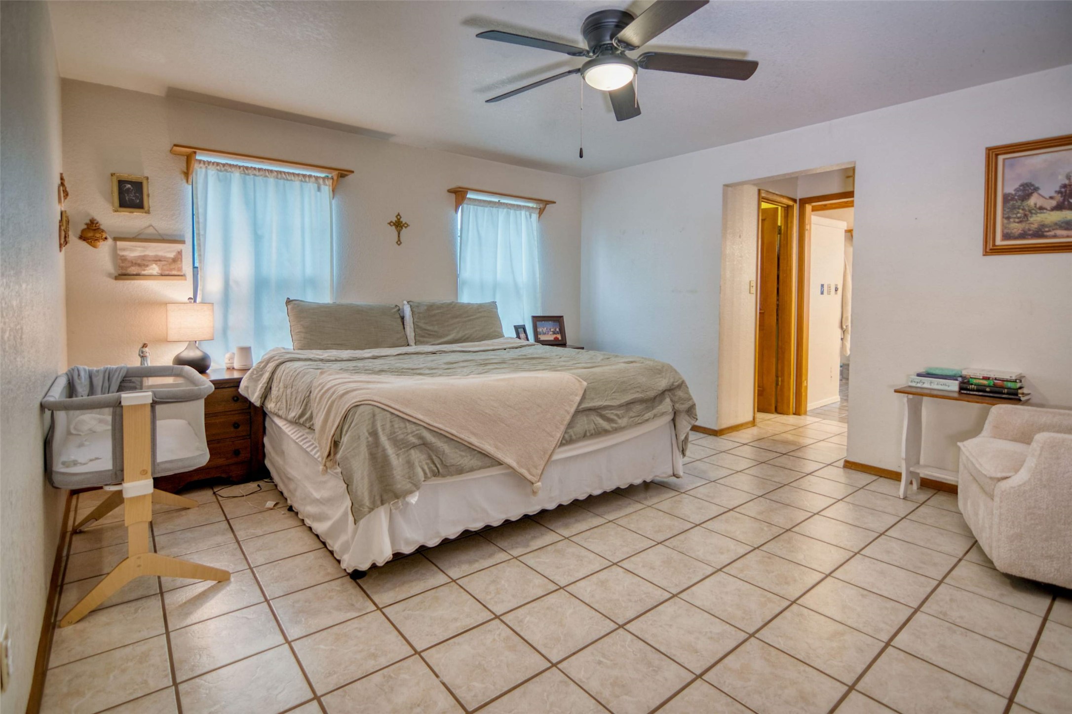 904 Bluebonnet Road Mason, TX 76856 - Photo 16 of 28 Spacious room featuring light-toned tile flooring, two windows with window treatments, a ceiling fan with integrated lighting, and a doorway with wood-finish trim