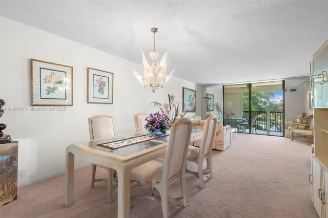a view of a dining room with furniture a chandelier and large windows