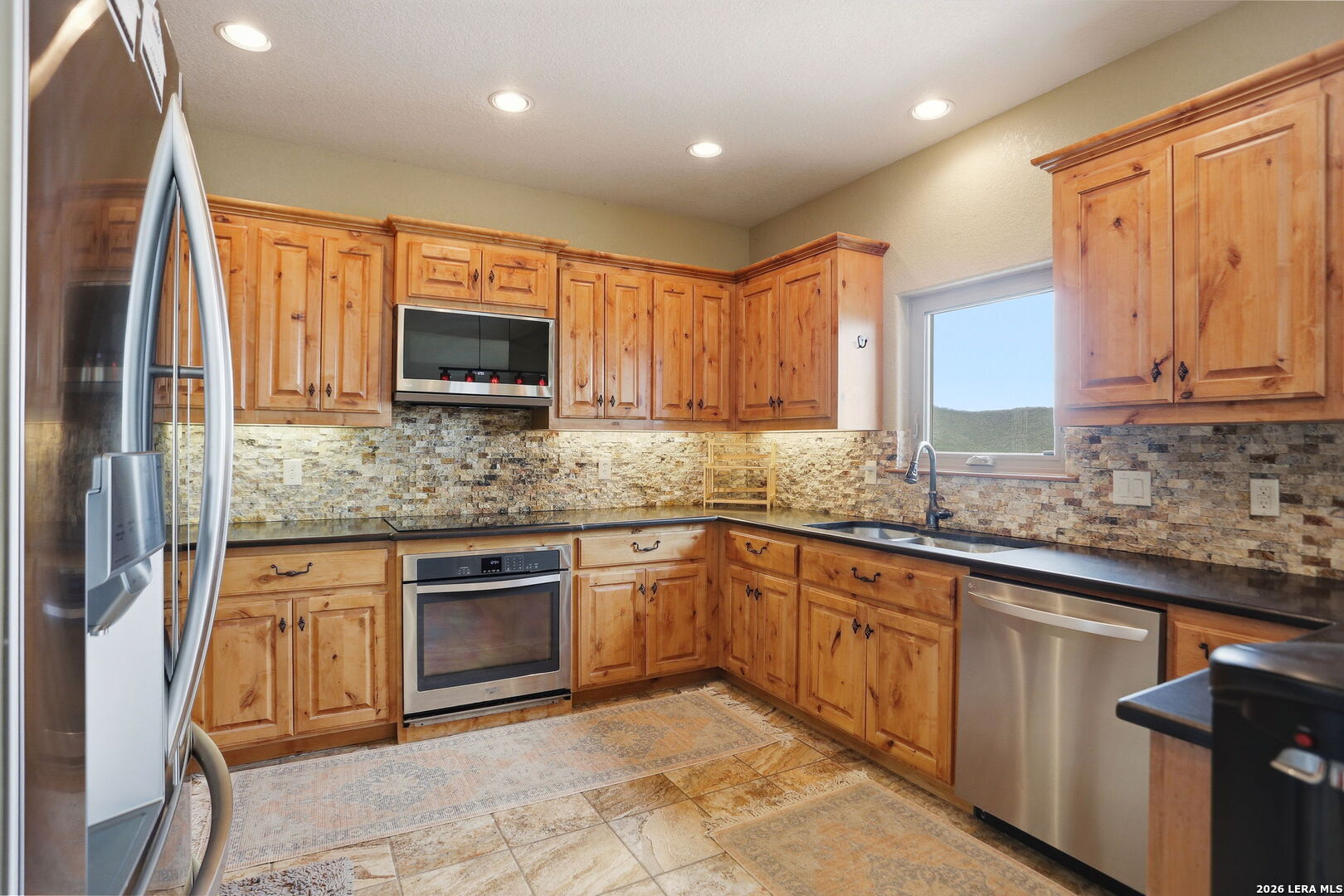 232 Doe Run Road Pipe Creek, TX 78063 - Photo 11 of 40 a kitchen with stainless steel appliances granite countertop a stove top oven a sink dishwasher and microwave oven