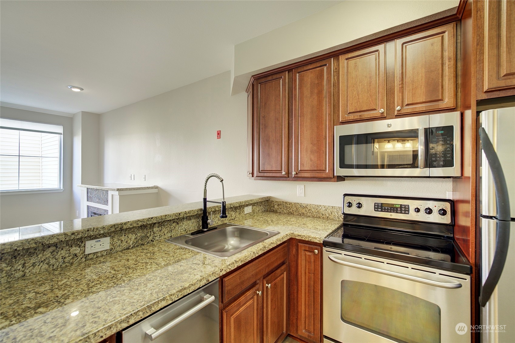 225 Logan Avenue South, Unit 108 Renton, WA 98057 - Photo 6 of 23 a kitchen with granite countertop a sink a stove and cabinets