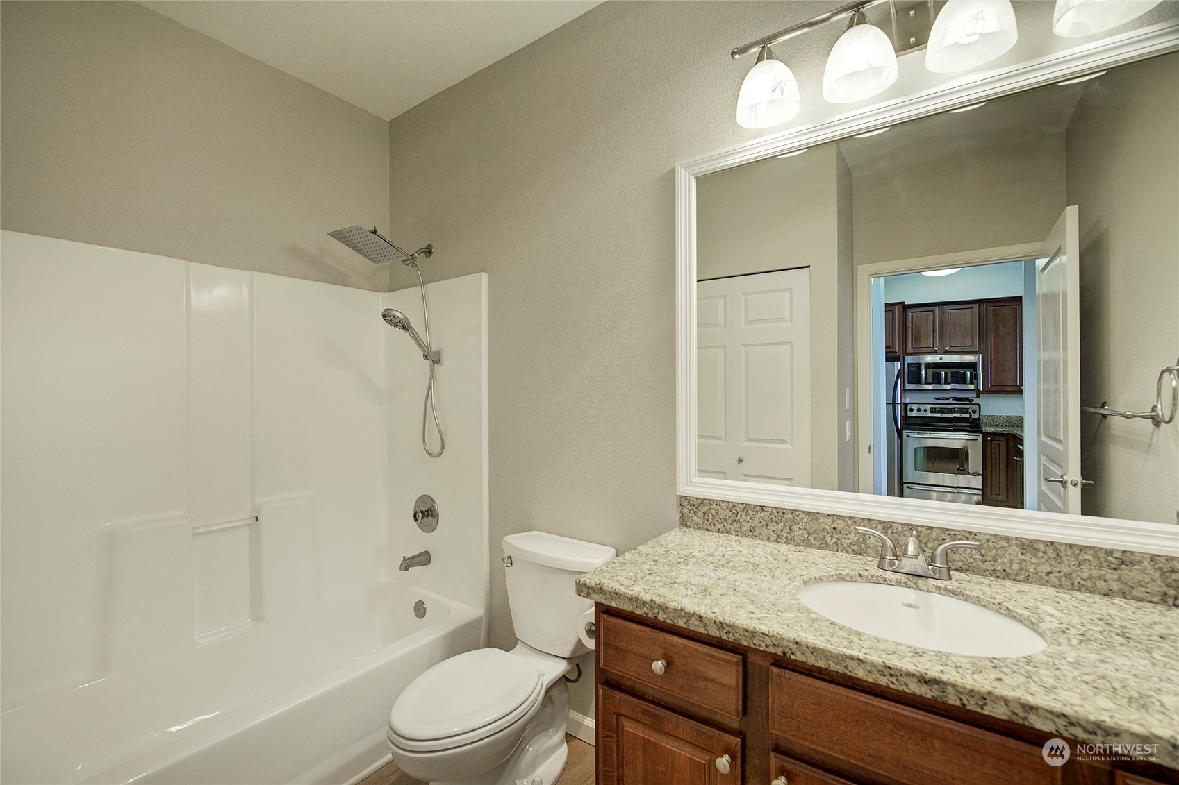 225 Logan Avenue South, Unit 108 Renton, WA 98057 - Photo 10 of 23 a bathroom with a granite countertop sink toilet a large mirror a bathtub and shower