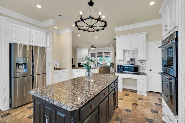 a kitchen with stainless steel appliances granite countertop a table chairs refrigerator and microwave
