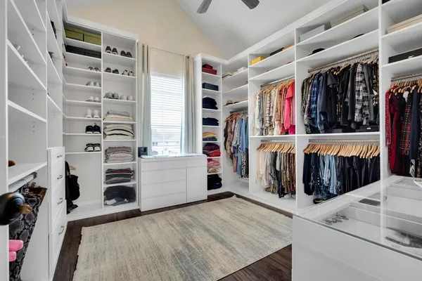 a view of walk in closet with clothes and shoes