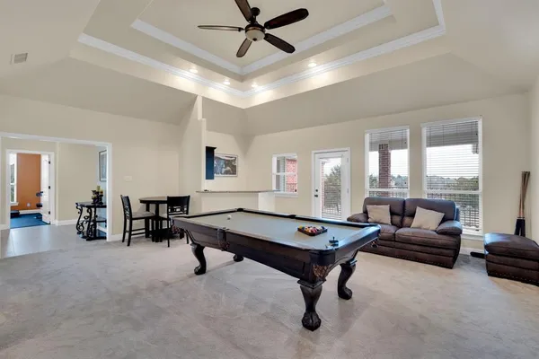 a living room with furniture pool table and a ceiling fan