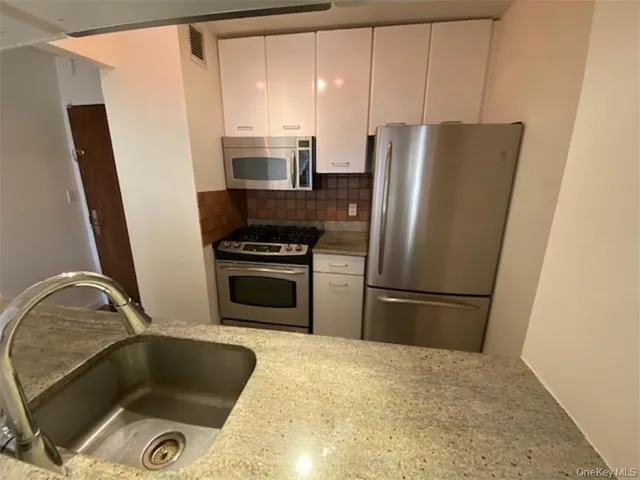 a kitchen with granite countertop a refrigerator and a sink