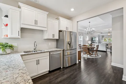 a kitchen with a refrigerator a white cabinets and wooden floor