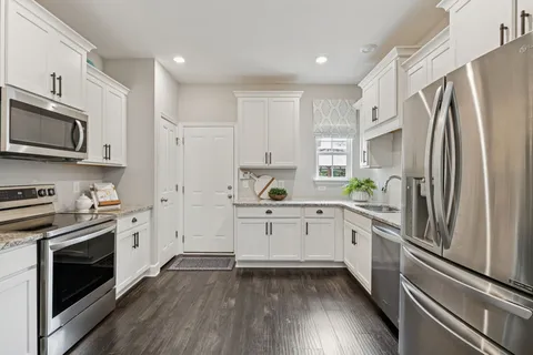 a kitchen with white cabinets white stainless steel appliances and wooden floors