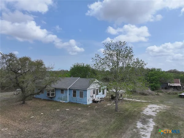 a view of a house with a big yard and large trees