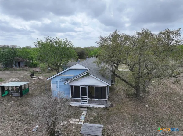 an aerial view of a house with a yard and trees in the background
