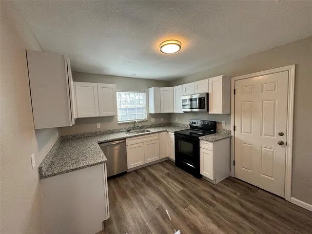 a kitchen with granite countertop a sink stove and refrigerator