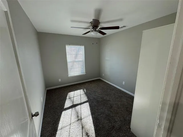 an empty room with windows and fan