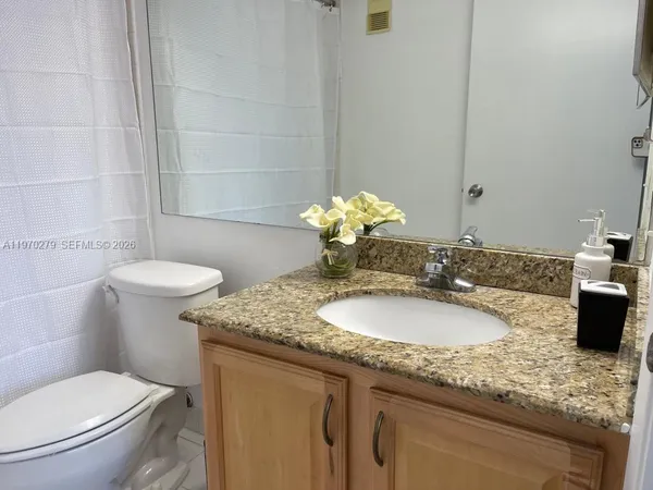 a bathroom with a granite countertop sink a toilet and a mirror