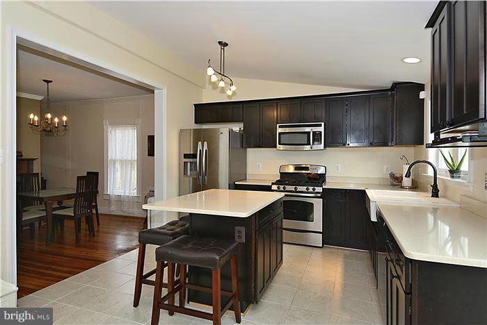 631 Ritchie Avenue Silver Spring, MD 20910 - Photo 14 of 30 a large kitchen with stainless steel appliances kitchen island granite countertop a table chairs and a refrigerator