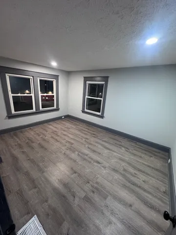 a view of an empty room with window and wooden floor