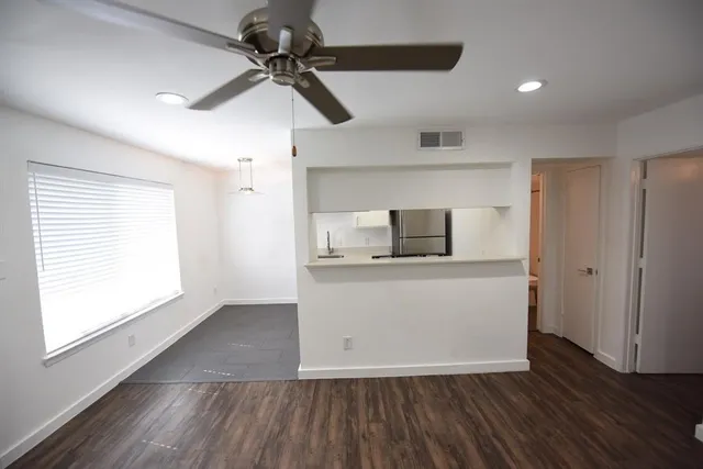 a view of kitchen and empty room with wooden floor