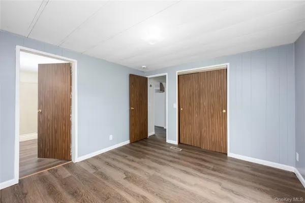a view of an empty room with wooden floor & closet