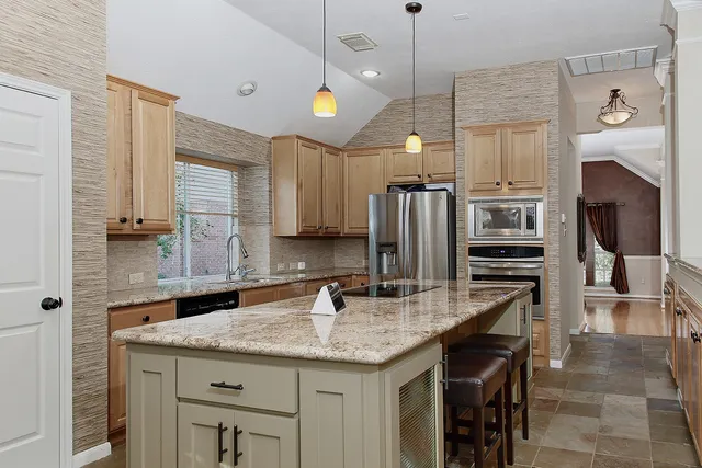 a kitchen with stainless steel appliances granite countertop a sink a stove and a refrigerator