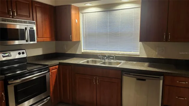 a kitchen with granite countertop stainless steel appliances a sink stove and cabinets