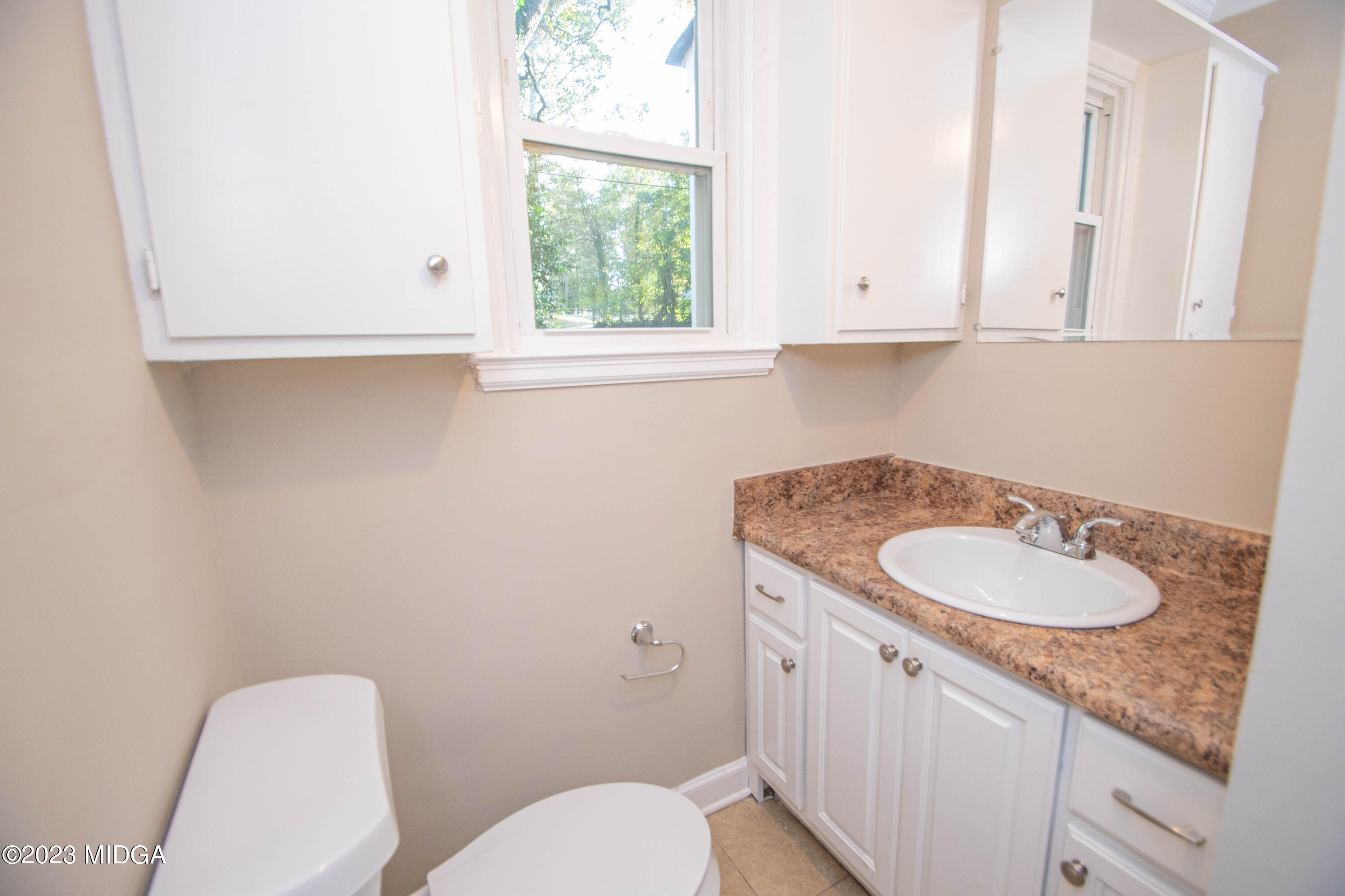 225 R Street Northwest Thomaston, GA 30286 - Photo 18 of 22 a bathroom with a granite countertop toilet a sink and a mirror