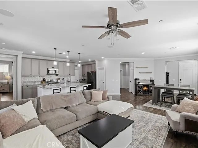 a living room with furniture kitchen view and a wooden floor