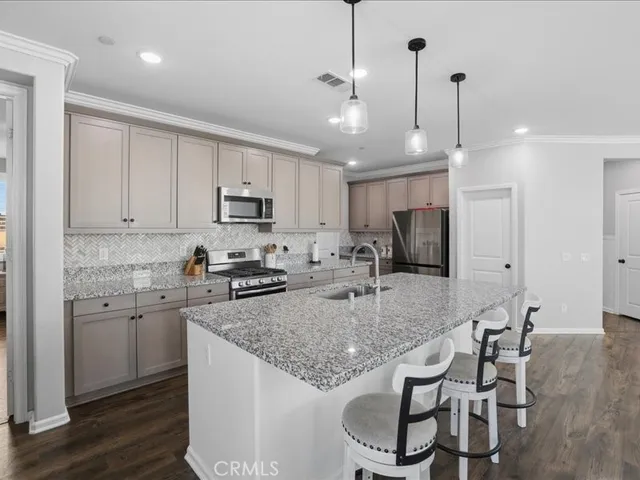 a kitchen with stainless steel appliances granite countertop a stove top oven a refrigerator a sink and chairs