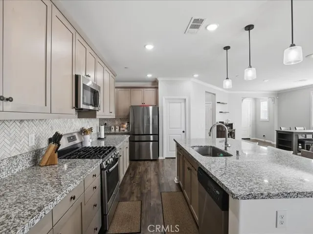 a kitchen with stainless steel appliances granite countertop a sink a stove and a refrigerator