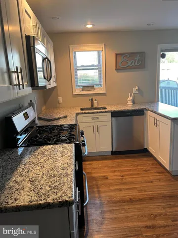 a kitchen with stainless steel appliances granite countertop a stove a sink and a microwave