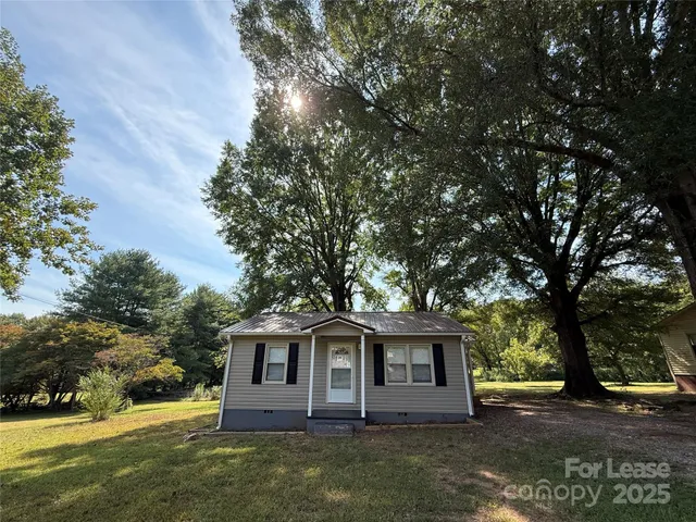 a view of a yard in front of a house with large trees