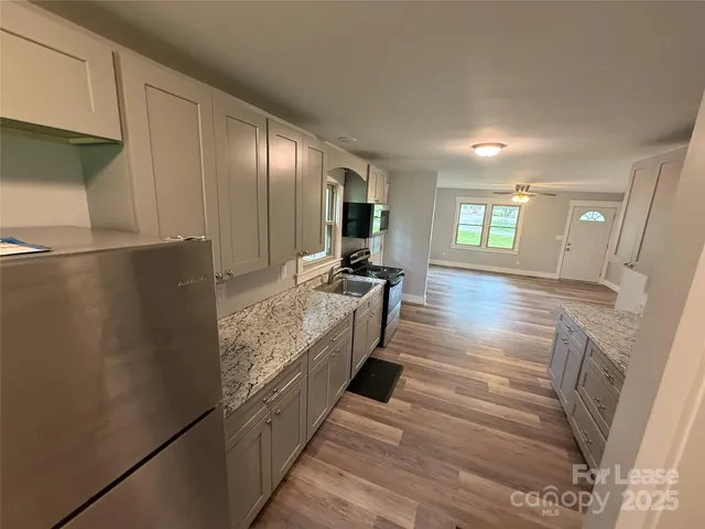 a large kitchen with kitchen island white cabinets and stainless steel appliances