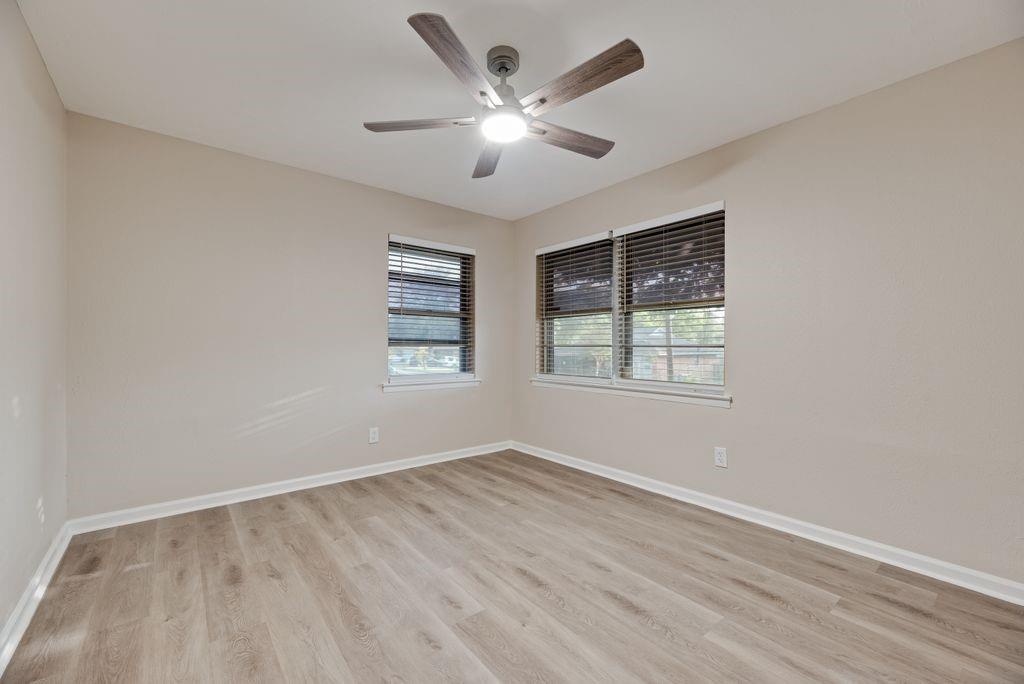 5706 Rocky Ridge Road Dallas, TX 75241 - Photo 18 of 31 an empty room with wooden floor ceiling fan and windows