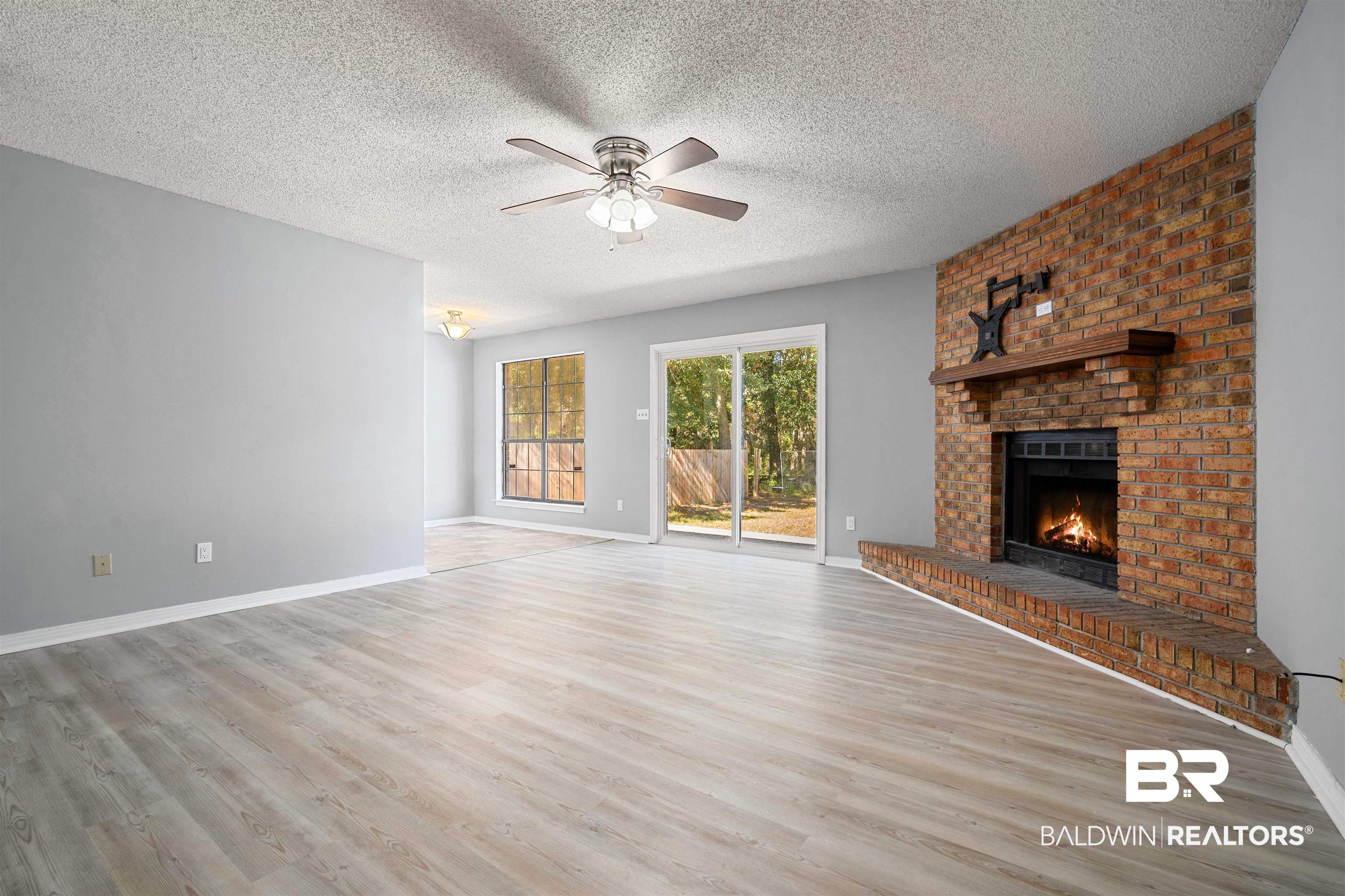 12910 Del Rio Street Grand Bay, AL 36541 - Photo 4 of 26 Unfurnished living room featuring a fireplace, a textured ceiling, light wood-style floors, and ceiling fan