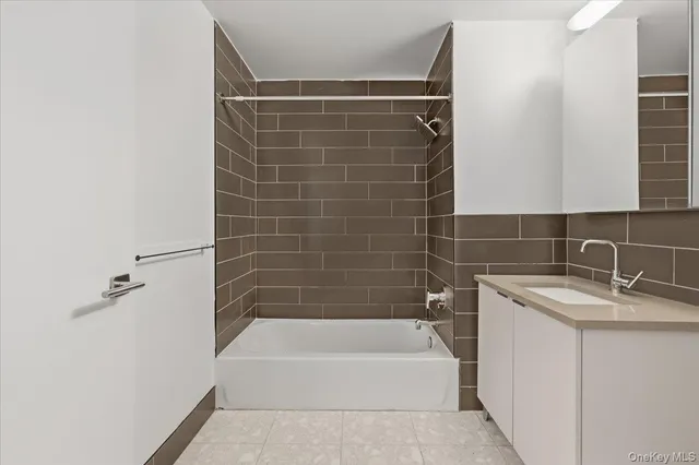 a bathroom with a granite countertop bathtub shower sink vanity and toilet