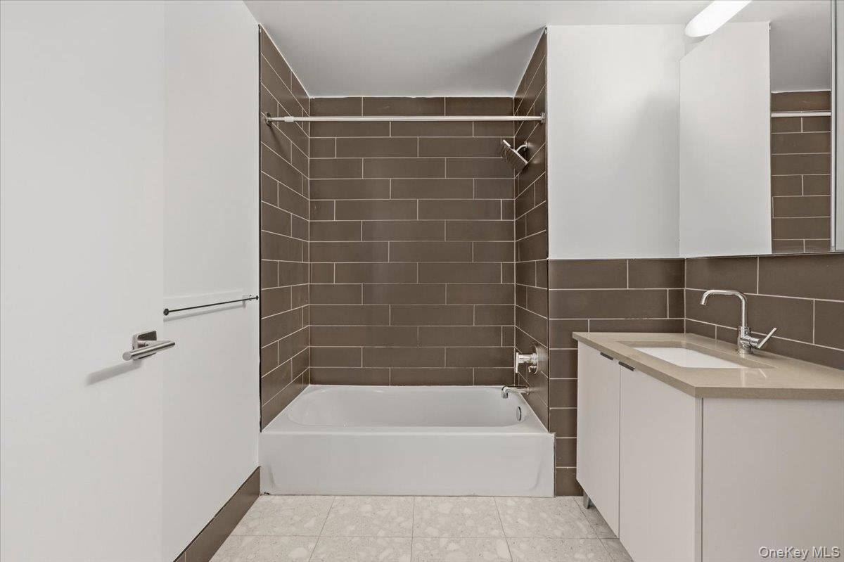 70 Fleet Street, Unit 19F Brooklyn, NY 11201 - Photo 16 of 32 a bathroom with a granite countertop bathtub shower sink vanity and toilet