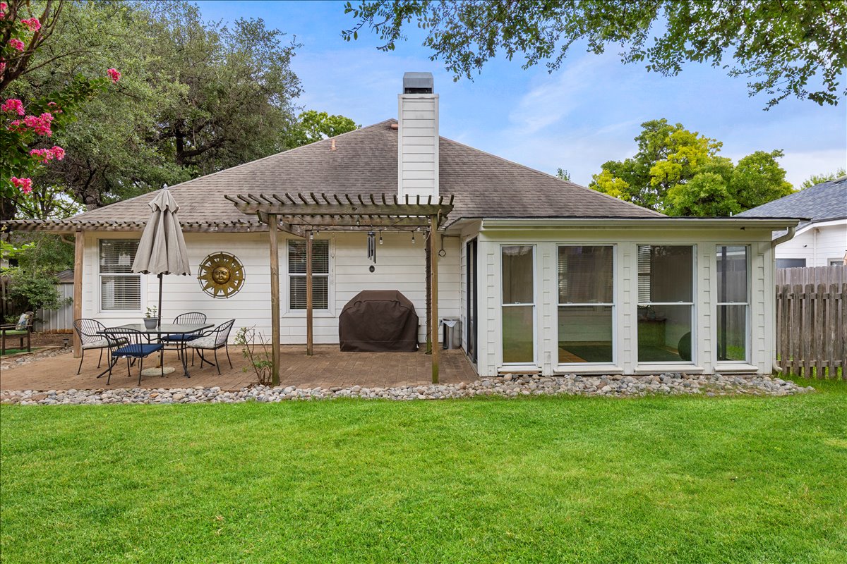 9012 Meacham Way Austin, TX 78749 - Photo 27 of 34 Expansive rear lawn featuring a white-sided exterior, a covered patio with a pergola, a sunroom with large windows, and a wood privacy fence