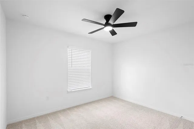 an empty room with a window and a ceiling fan
